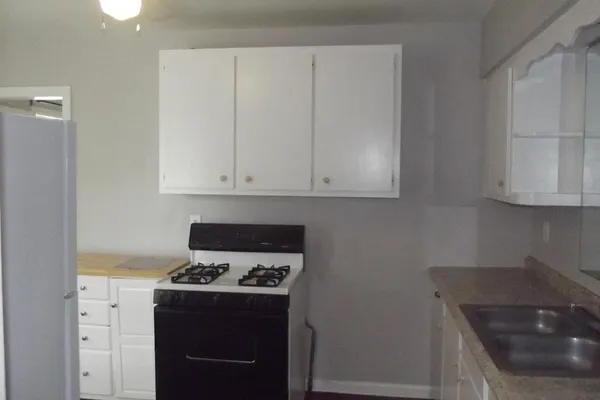 a kitchen with granite countertop a sink a stove and cabinets
