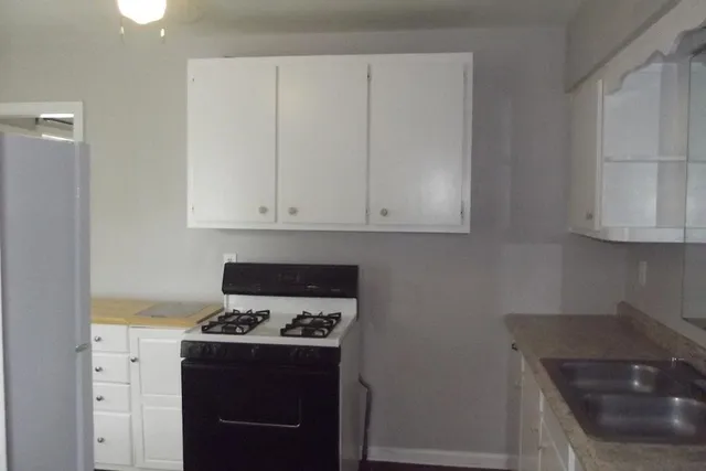 a kitchen with granite countertop a sink a stove and cabinets