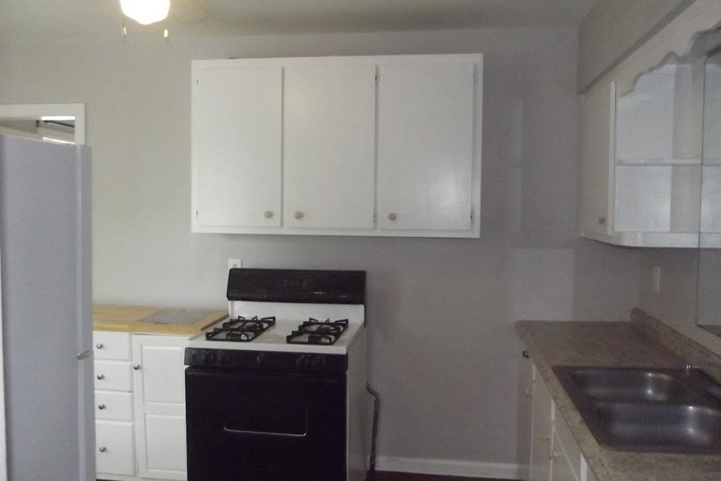 1702 42nd Street Columbus, GA 31904 - Photo 6 of 13 a kitchen with granite countertop a sink a stove and cabinets