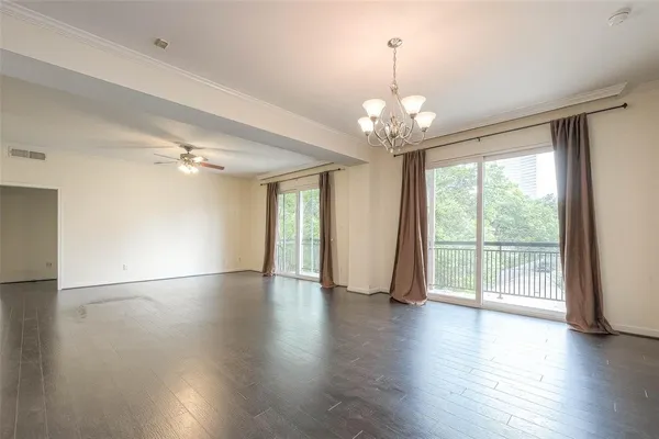 a view of an empty room with wooden floor and a ceiling fan