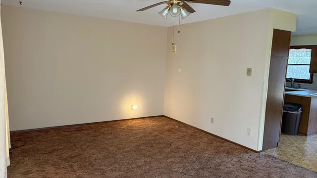 an empty room with a chandelier fan and closet