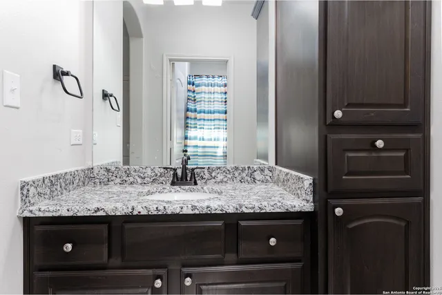 a bathroom with a granite countertop sink and a mirror