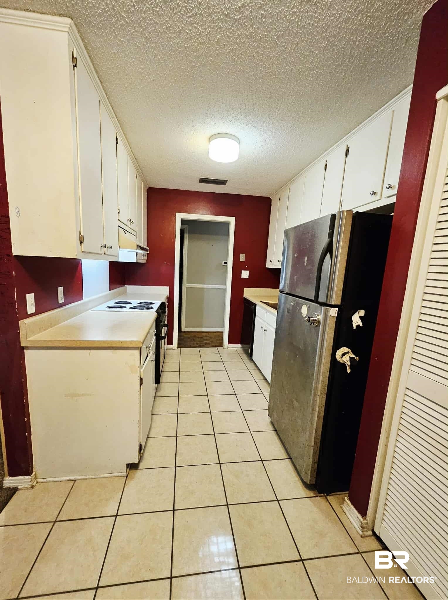 324 Vanderbilt Drive Mobile, AL 36608 - Photo 5 of 17 Kitchen with freestanding refrigerator, a textured ceiling, light countertops, white cabinets, and white electric range oven
