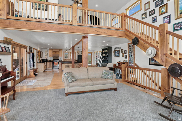 715 Ranch Loop Road Preston, ID 83263 - Photo 6 of 77 Open-concept living space with a high ceiling, exposed wood beams, and a light wood staircase leading to an upper-level balcony
