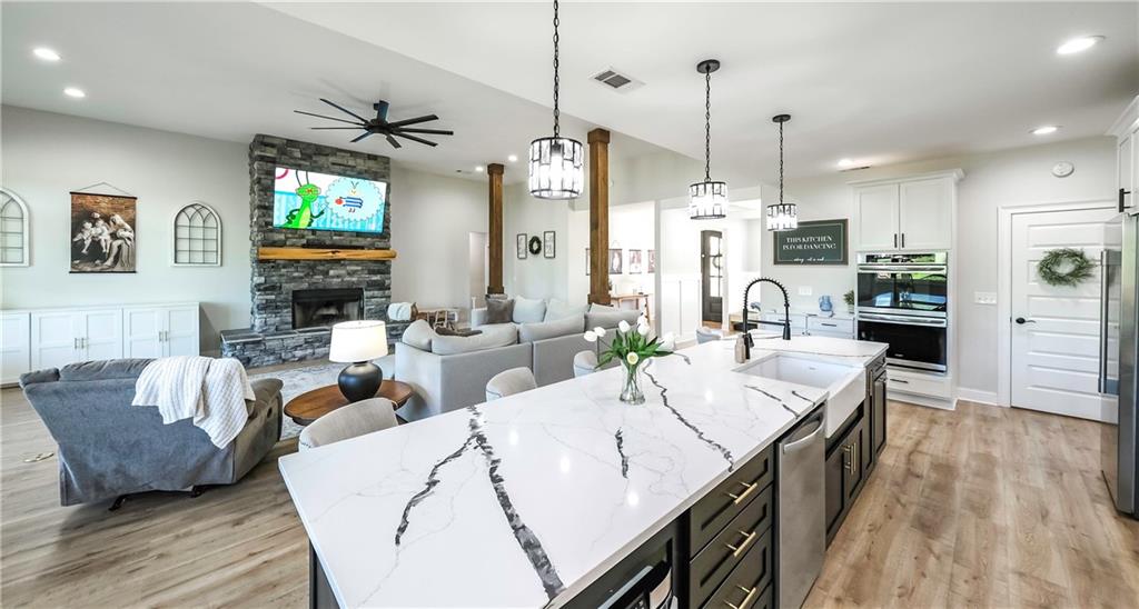 2392 Welcome Road Roopville, GA 30170 - Photo 37 of 65 a living room with stainless steel appliances kitchen island granite countertop furniture a rug a kitchen island a fireplace and a wooden floor