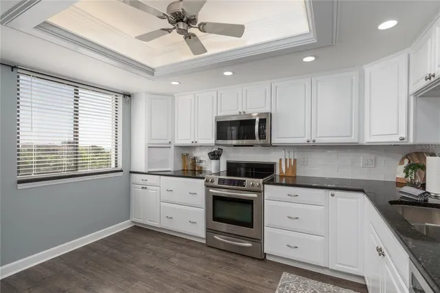 a kitchen with white cabinets stainless steel appliances and a window