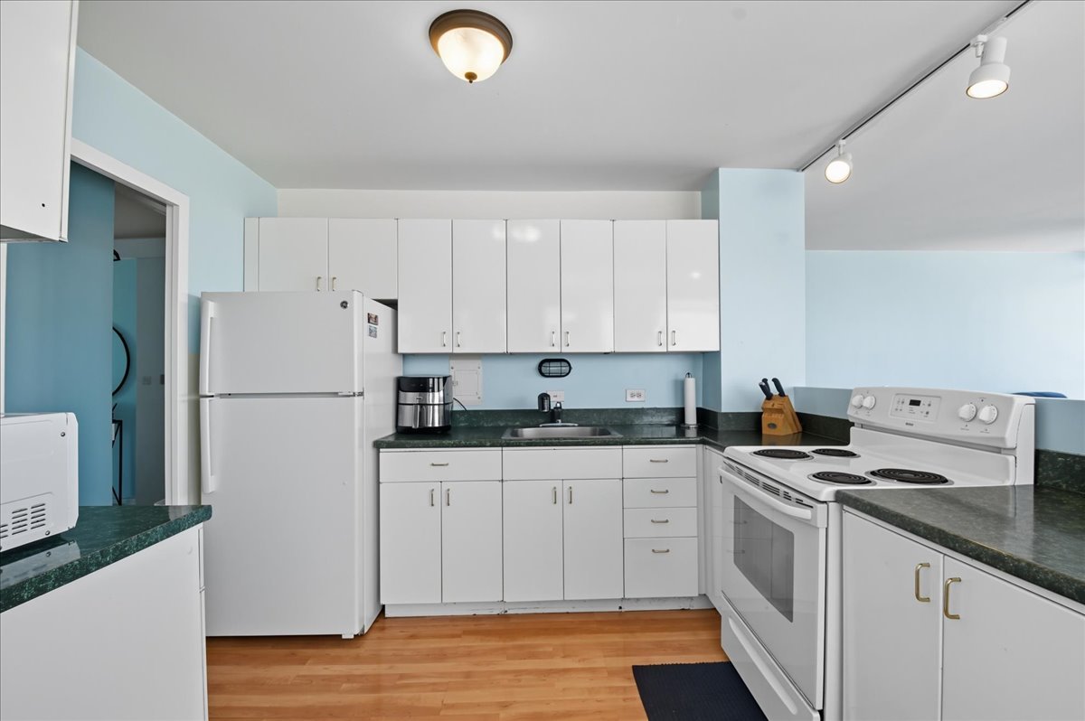 5701 North Sheridan Road, Unit 26B Chicago, IL 60660 - Photo 6 of 18 a kitchen with granite countertop a refrigerator sink stove and white cabinets