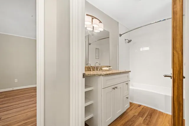 a bathroom with a granite countertop sink mirror and a bathtub