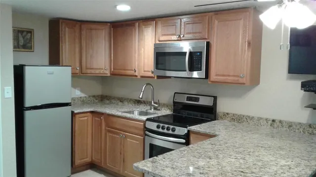 a kitchen with stainless steel appliances granite countertop a refrigerator stove top oven and sink