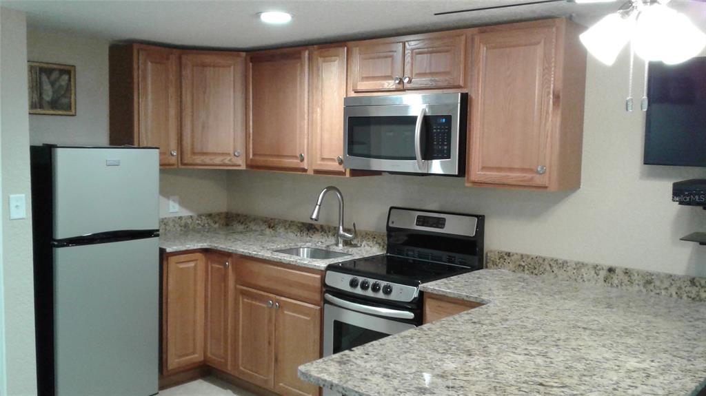 2512 Musselwhite Avenue, Unit 3 Orlando, FL 32804 - Photo 8 of 9 a kitchen with stainless steel appliances granite countertop a refrigerator stove top oven and sink