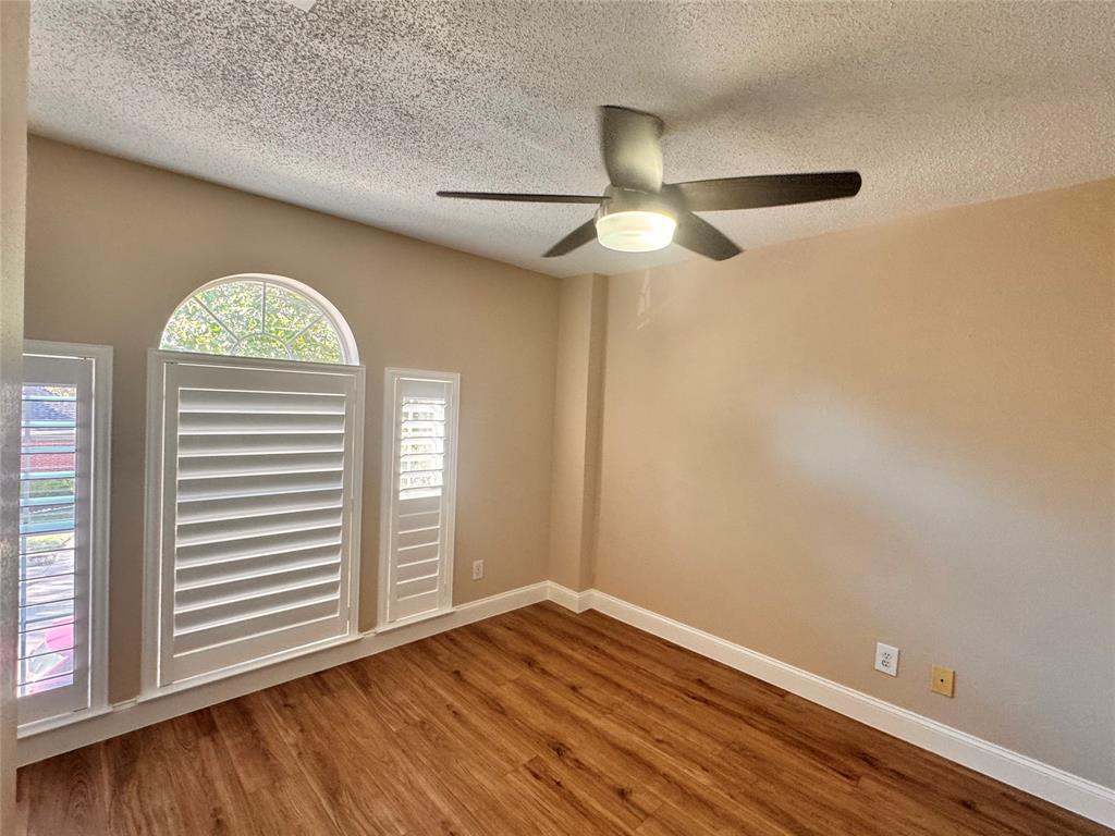9435 Blue Jay Way Irving, TX 75063 - Photo 23 of 27 an empty room with wooden floor chandelier fan and windows
