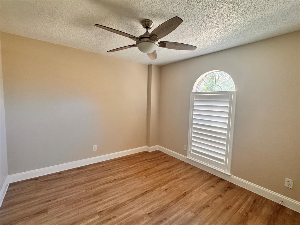 9435 Blue Jay Way Irving, TX 75063 - Photo 25 of 27 an empty room with wooden floor fan and windows