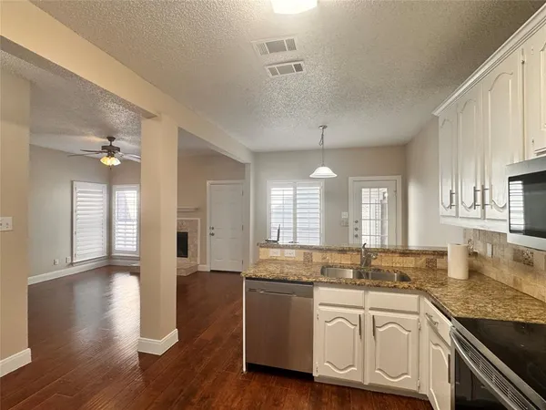 a kitchen with granite countertop a sink cabinets stainless steel appliances and a window