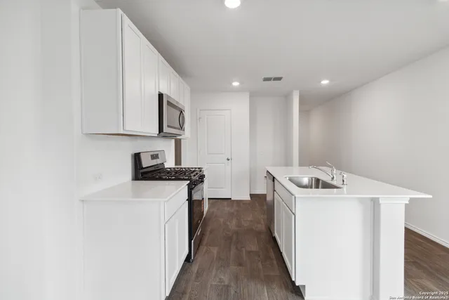 a kitchen with a stove sink and cabinets