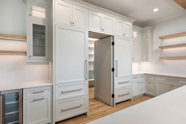 a large white kitchen with a large window appliances and cabinets