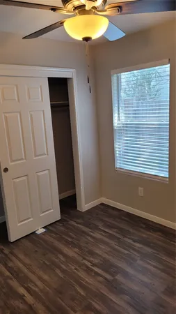 an empty room with wooden floor fan and windows
