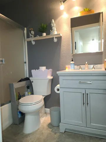 a bathroom with a toilet sink vanity and mirror