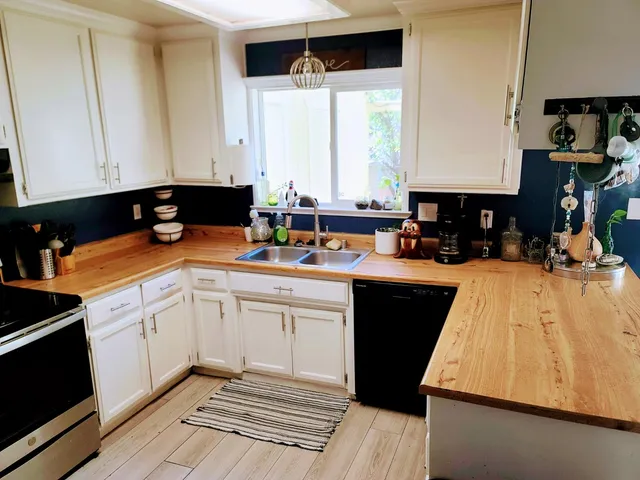a kitchen with a sink dishwasher and white cabinets with wooden floor