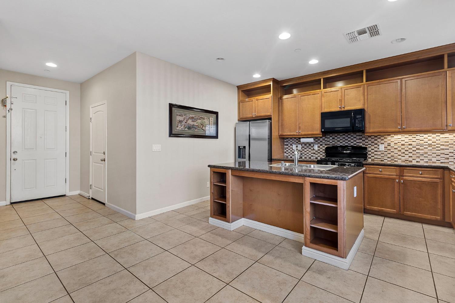 7525 Eldred Way Sacramento, CA 95829 - Photo 12 of 38 kitchen featuring open shelves, backsplash, light tile patterned flooring, recessed lighting, and black appliances