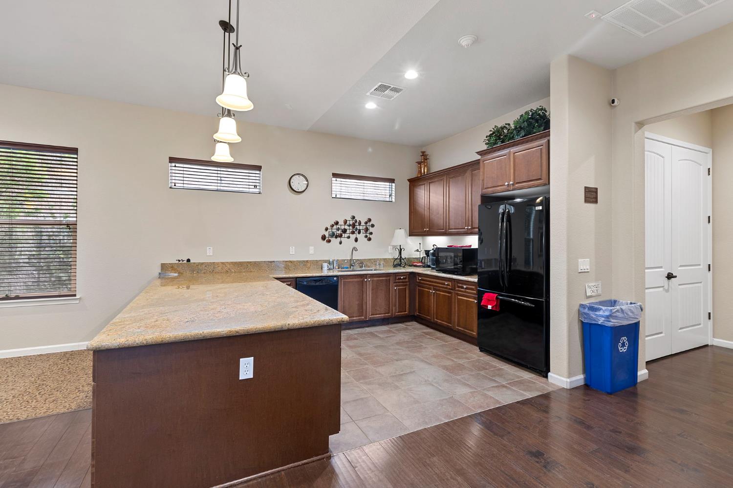 7525 Eldred Way Sacramento, CA 95829 - Photo 29 of 38 kitchen with a peninsula, black appliances, hanging light fixtures, light wood-style flooring, and recessed lighting