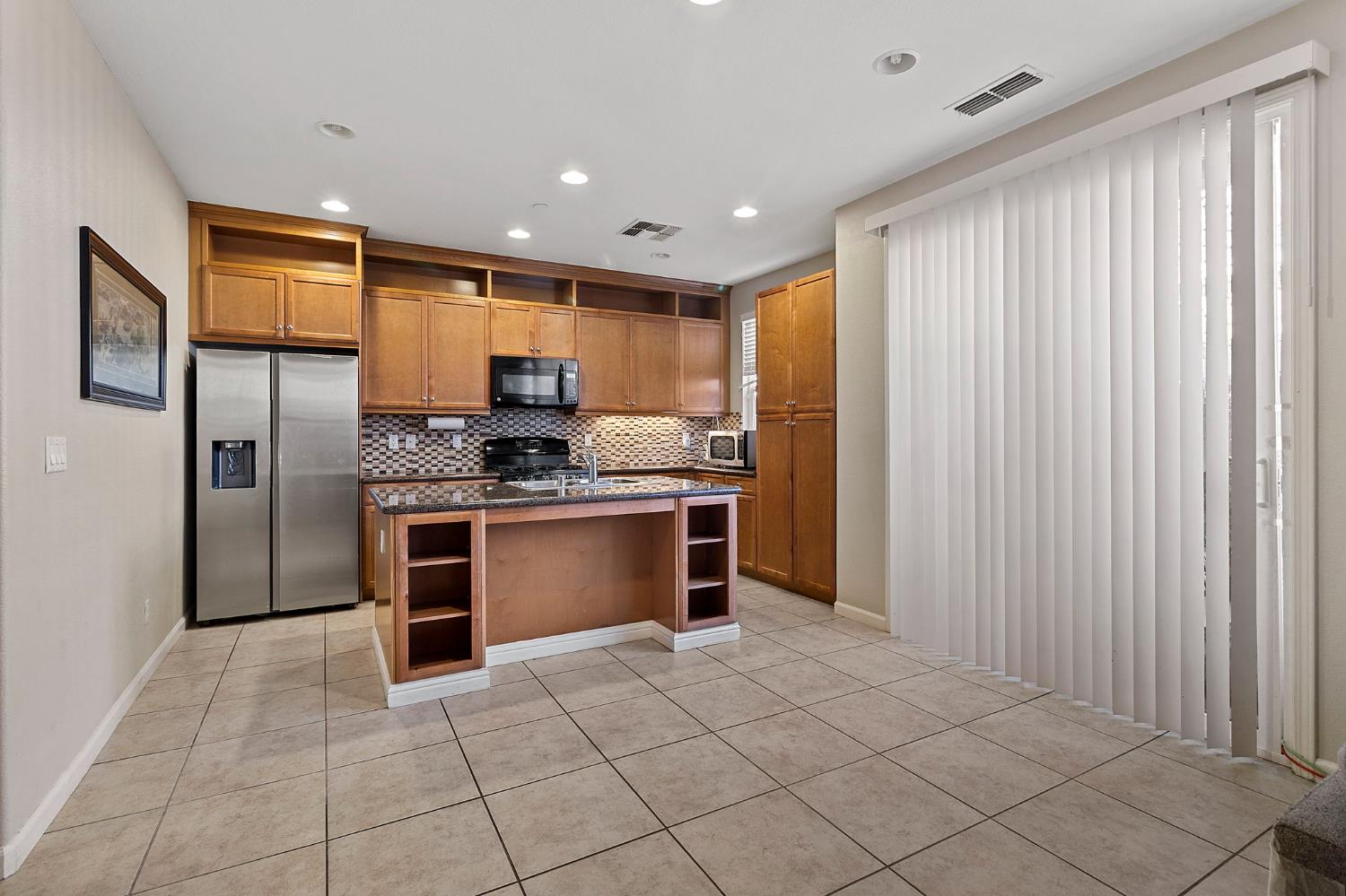7525 Eldred Way Sacramento, CA 95829 - Photo 8 of 38 kitchen with open shelves, black appliances, decorative backsplash, a kitchen island with sink, and recessed lighting