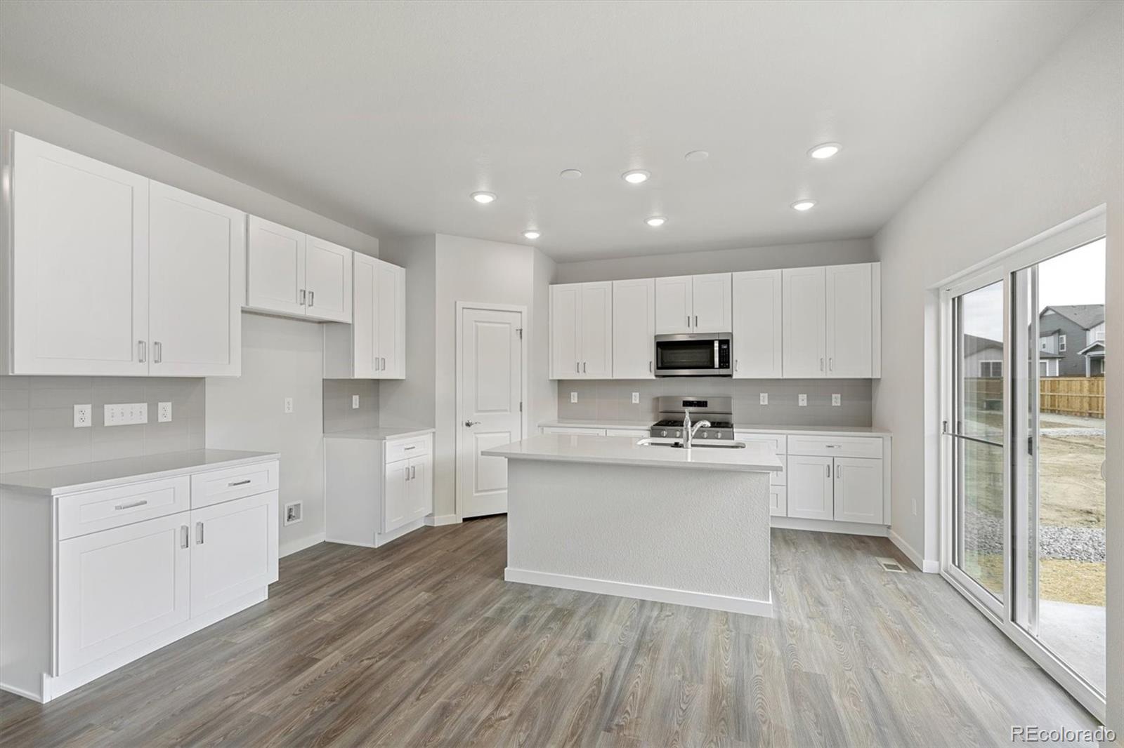 1414 Farmstead Street Brighton, CO 80601 - Photo 12 of 26 a kitchen with white cabinets and stainless steel appliances