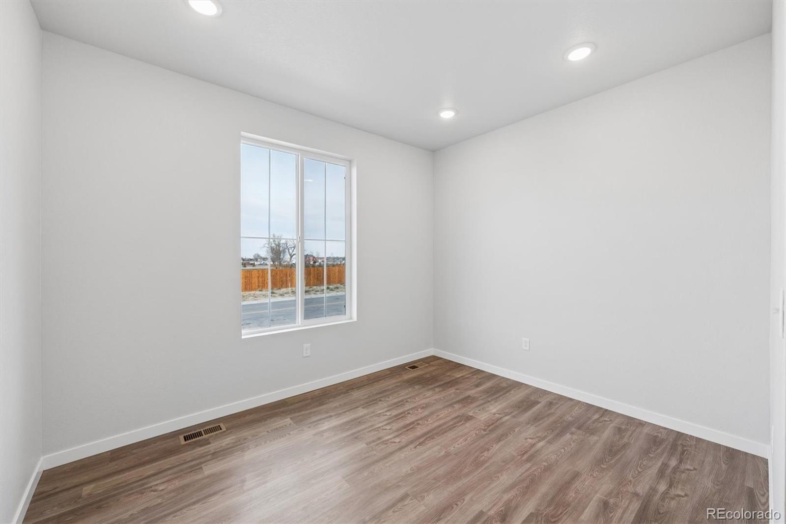 1414 Farmstead Street Brighton, CO 80601 - Photo 3 of 26 an empty room with wooden floor and windows