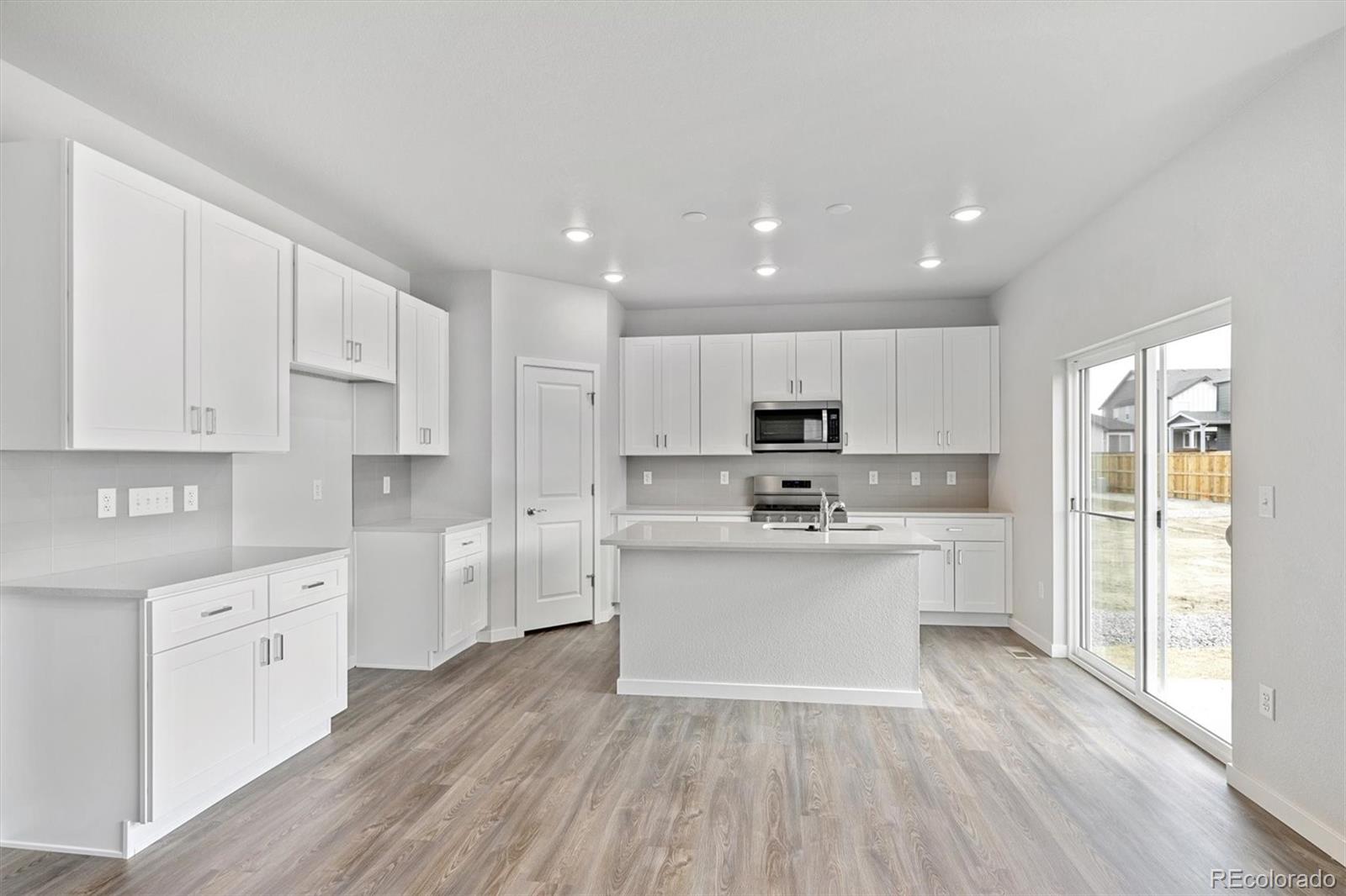1414 Farmstead Street Brighton, CO 80601 - Photo 7 of 26 a kitchen with stainless steel appliances sink refrigerator and cabinets