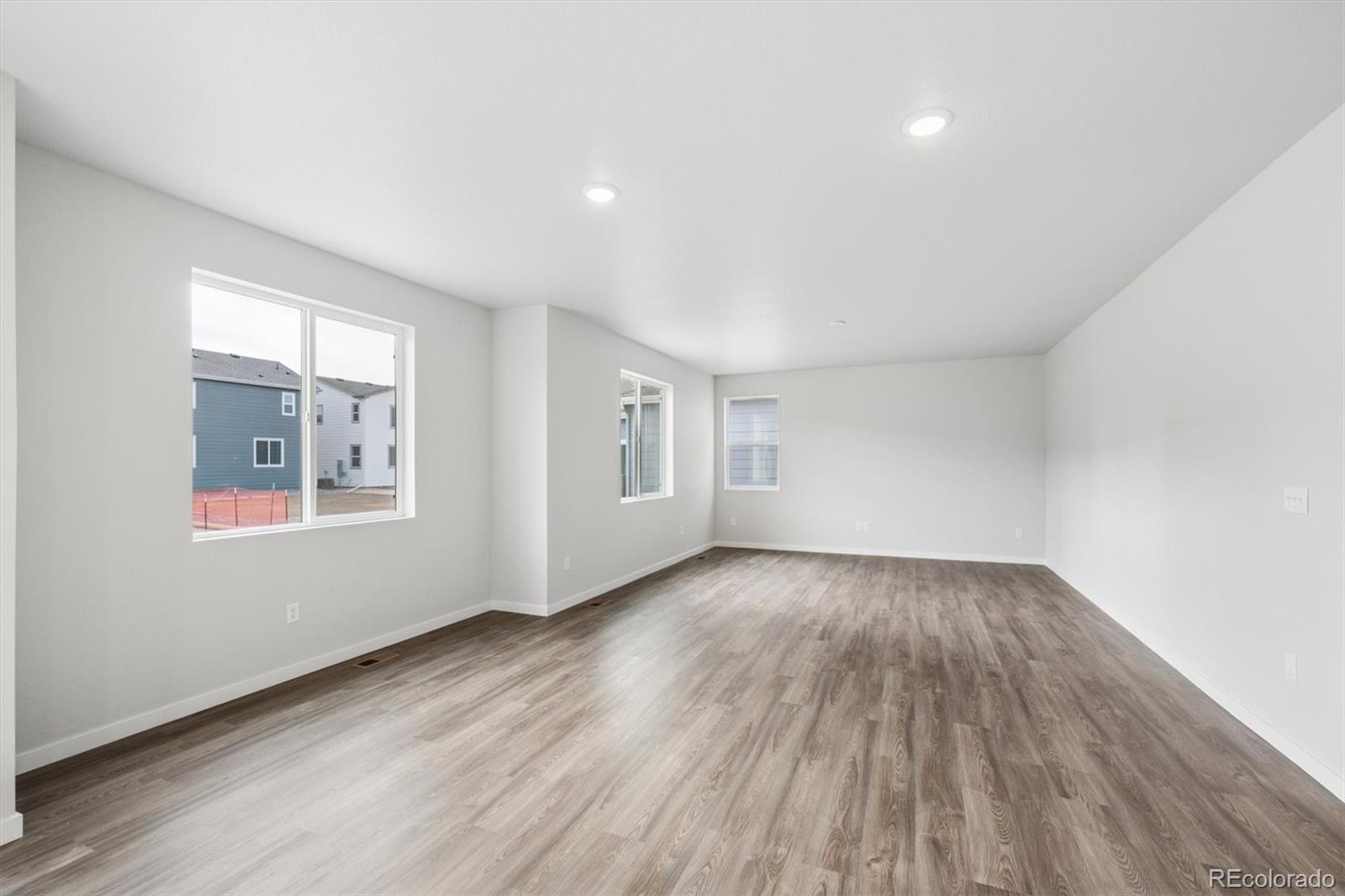 1414 Farmstead Street Brighton, CO 80601 - Photo 9 of 26 an empty room with wooden floor and windows