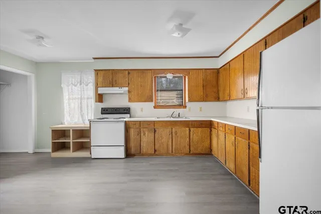 a kitchen with granite countertop a stove a sink and a refrigerator
