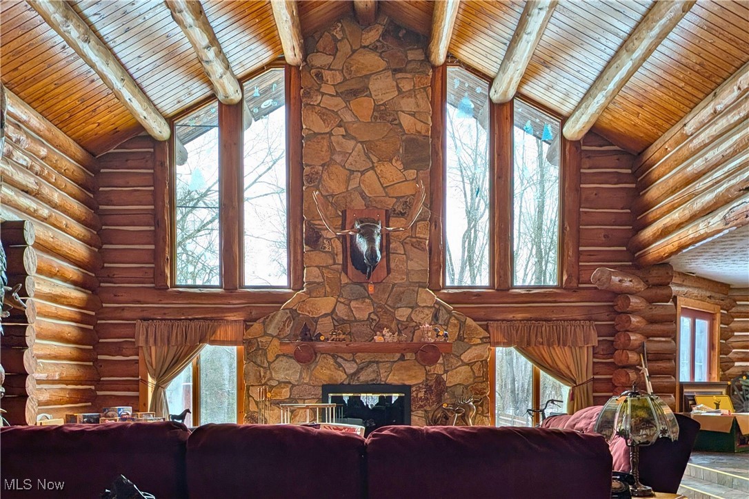 8026 Lee Road Northwest Malvern, OH 44644 - Photo 4 of 44 Living area with high vaulted ceiling, log walls, plenty of natural light, a fireplace, and a wood ceiling with exposed beams