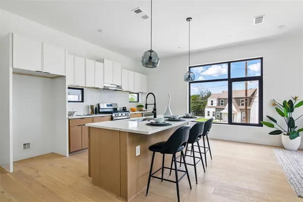 a kitchen with stainless steel appliances granite countertop sink stove and white cabinets with wooden floor