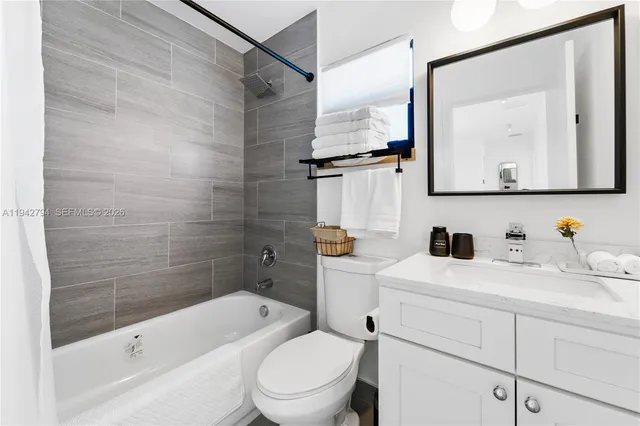 a bathroom with a granite countertop sink mirror vanity bathtub and toilet