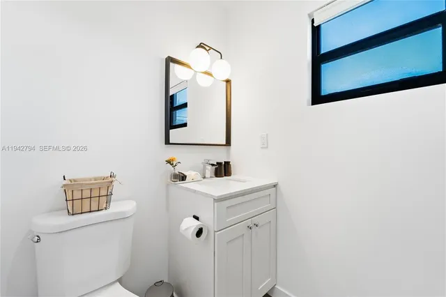 a bathroom with a toilet sink vanity and mirror