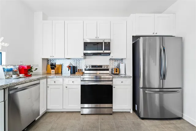 a kitchen with stainless steel appliances white cabinets and a refrigerator