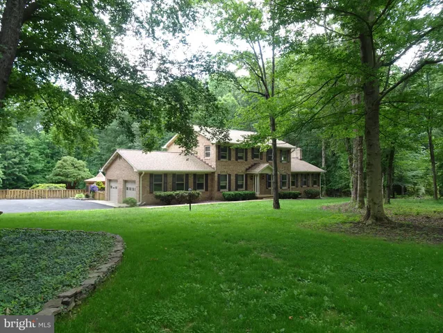 a view of a big house with a big yard and large trees