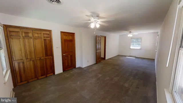 an empty room with ceiling fan and window