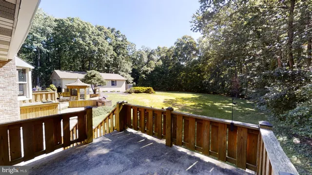 a view of a deck with chairs and yard with wooden fence