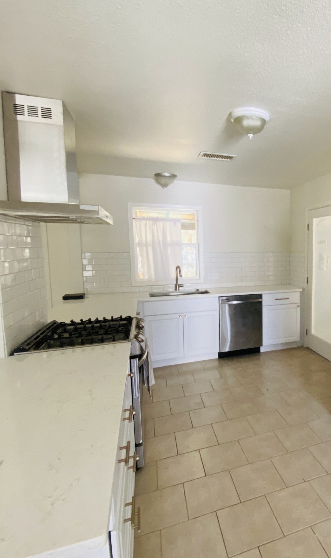 2406 Patsy Parkway Austin, TX 78744 - Photo 2 of 9 Kitchen featuring white cabinets, backsplash, range hood, stainless steel appliances, and light stone countertops