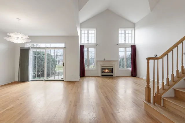 an empty room with wooden floor fireplace and windows