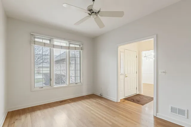 a view of an empty room and window and chandelier fan