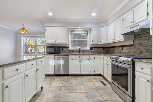 a kitchen with granite countertop stainless steel appliances a refrigerator sink stove and cabinets