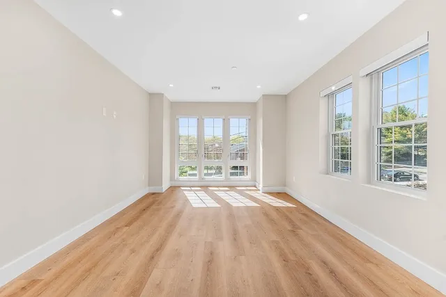 a view of an empty room with a window and wooden floor