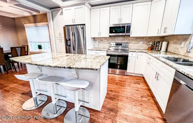 a kitchen with granite countertop stainless steel appliances a sink and a refrigerator