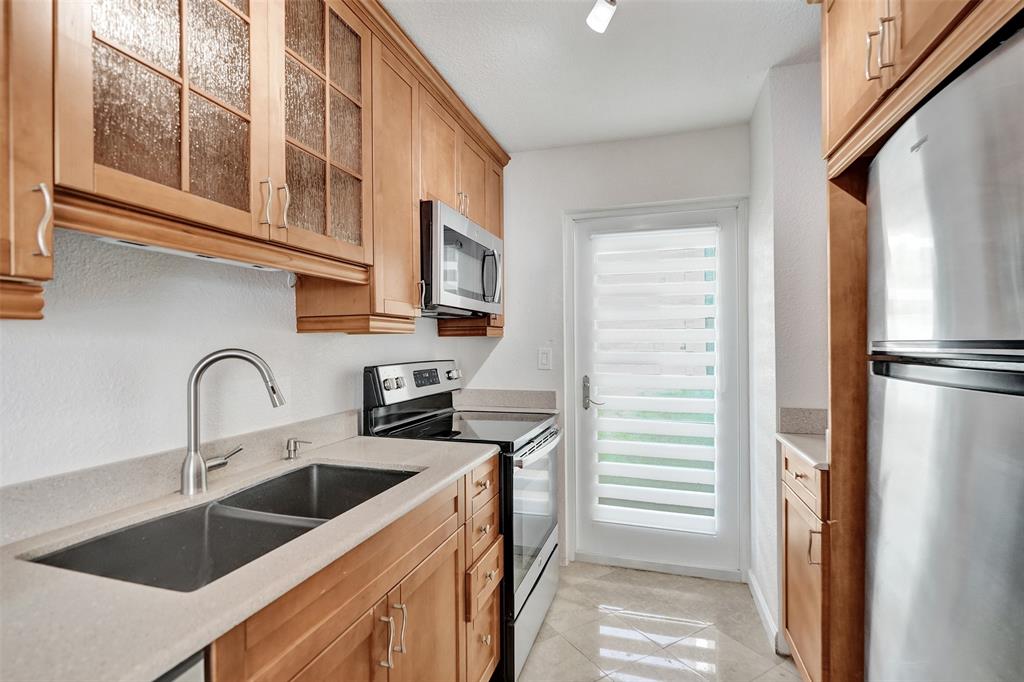 710 North Ocean Boulevard, Unit 910 Pompano Beach, FL 33062 - Photo 11 of 65 a kitchen with stainless steel appliances granite countertop a sink and a refrigerator