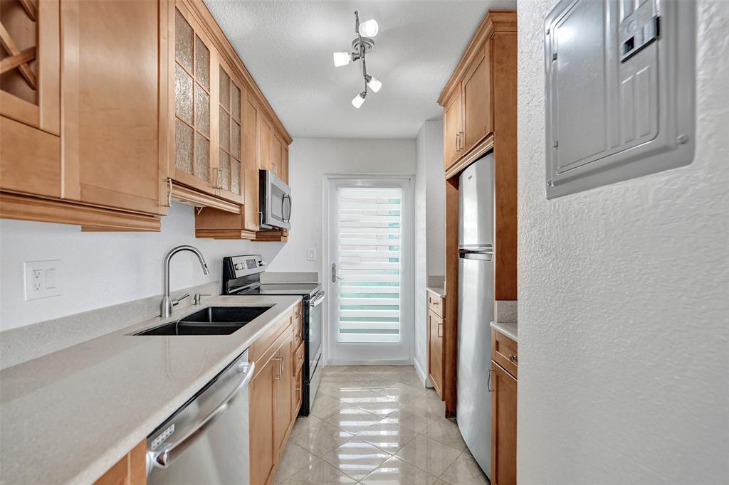 710 North Ocean Boulevard, Unit 910 Pompano Beach, FL 33062 - Photo 9 of 65 a kitchen with stainless steel appliances granite countertop a sink and dishwasher a refrigerator with wooden cabinets