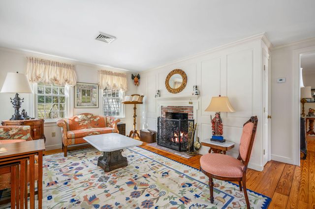 a living room with furniture a rug a fireplace and a window