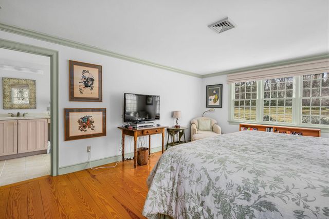 a bedroom with a bed a table and three large mirror with wooden floor