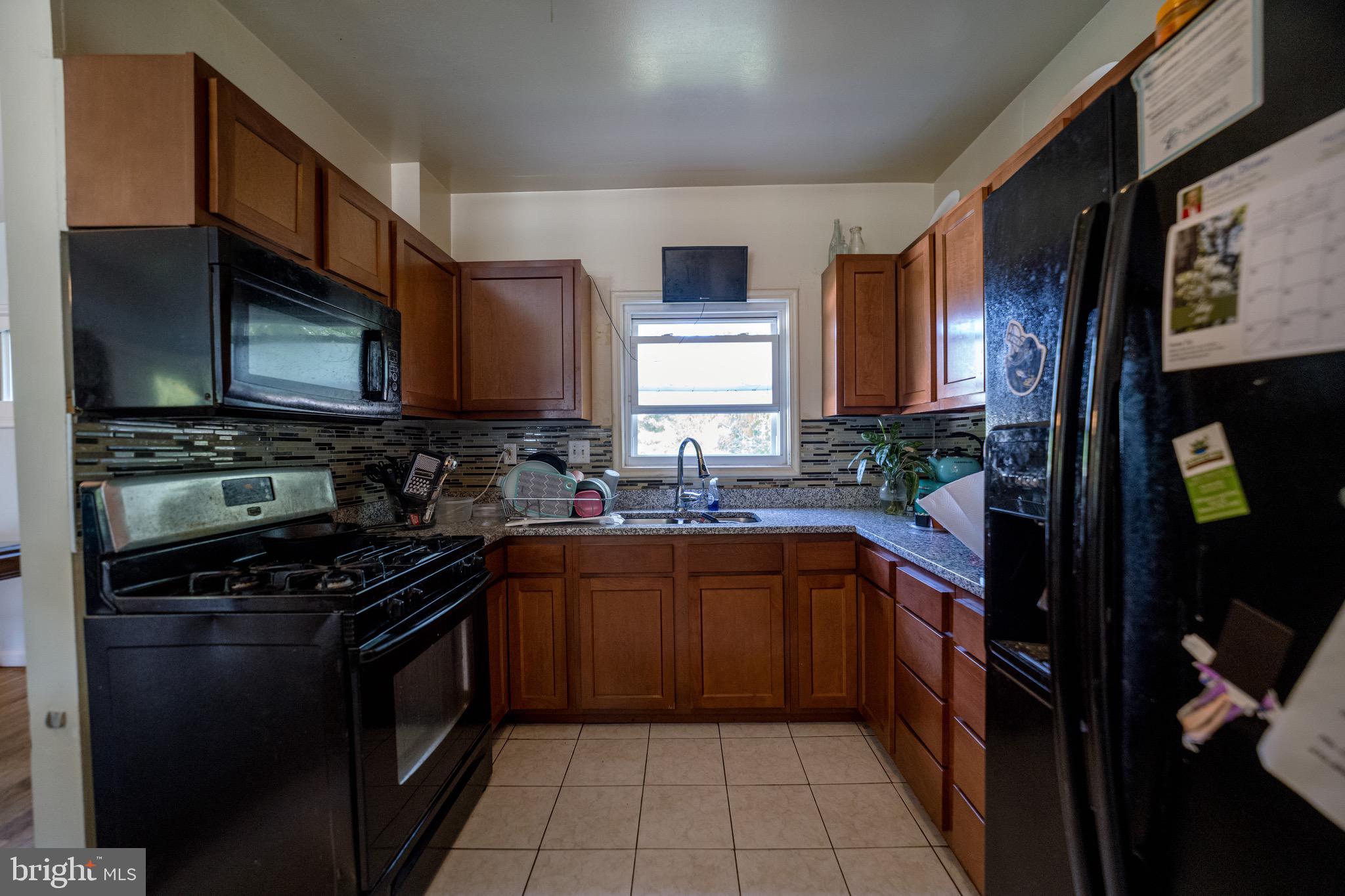 4125 Ronis Road Pikesville, MD 21208 - Photo 27 of 40 a kitchen with stainless steel appliances a stove sink microwave and cabinets