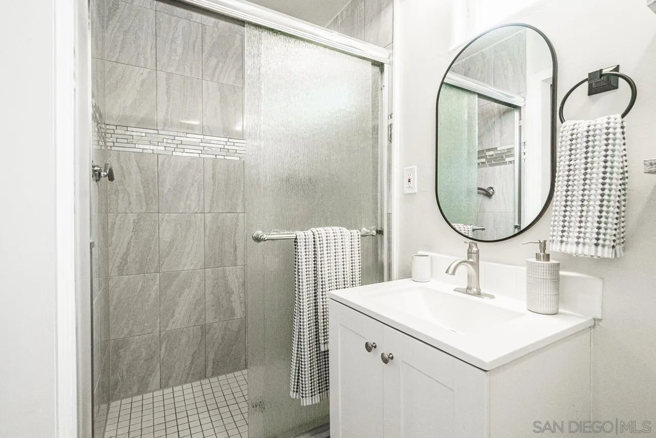 9026 Avocado Street Spring Valley, CA 91977 - Photo 19 of 27 a bathroom with a sink a mirror a vanity and a shower